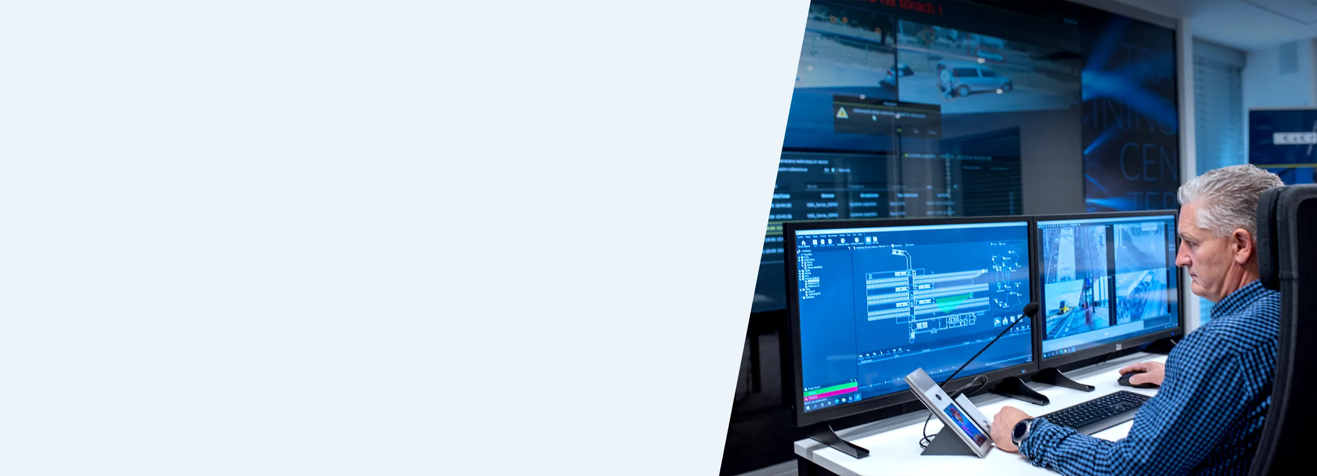 Control Room Operator Man in control room using multiple screens and an intercom for security monitoring.