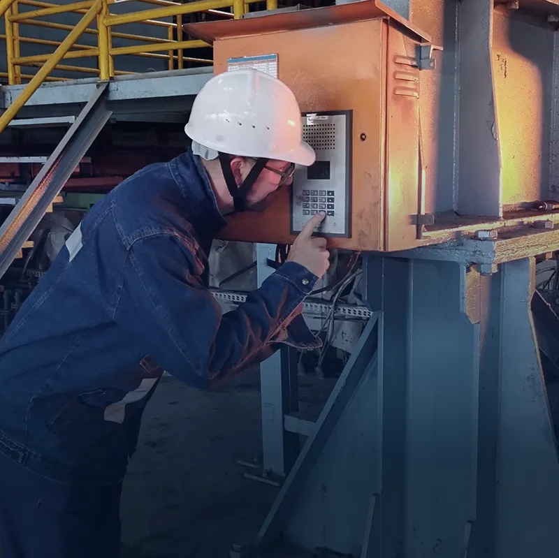 Worker using industrial intercom unit beside machinery in production area Worker in protective gear operating an industrial intercom mounted on machinery in the plant