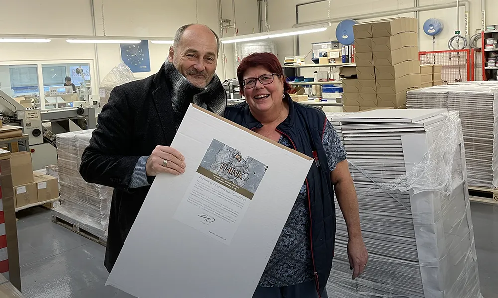 Business Partners Celebrate Success Two smiling business partners in a factory holding a certificate, celebrating a successful collaboration.